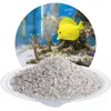 A pile of aquarium gravel in front of a circular image of a coral reef aquarium with a yellow fish. Produktbild-Vorschau