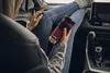 A person sitting in a car with their legs crossed, holding a Contigo travel mug. Anteprima dell’immagine prodotto