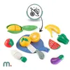 A collection of toy fruits and vegetables, including a corn cob, strawberry, orange, lemon, banana, green pepper, watermelon slice, eggplant, and carrot, arranged on a white background with a blue cutting board and a knife. A circular icon with a knife cut Podgląd zdjęcia produktu