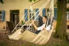 A woman relaxing in a hammock chair hanging from a tree in a garden. Náhled obrázku produktu