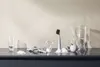 A collection of glassware and a soap dispenser on a dark reflective surface. Anteprima dell’immagine prodotto