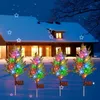 Four illuminated solar cypress trees in the snow in front of a house at night. Anteprima dell’immagine prodotto