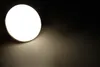 A close-up shot of a round LED light fixture emitting a warm white light onto a dark surface. Produktbild-Vorschau
