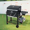 A black charcoal grill is shown outdoors on a lawn with dimensions indicated by orange lines and text. Anteprima dell’immagine prodotto