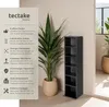 A tall, narrow black shelf unit is shown next to a large potted plant, with text describing the product's features on the left side of the image. Produktbild-Vorschau