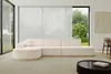 A modern living room with a large sectional sofa in front of a window with sheer curtains.