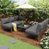A patio furniture set is arranged on a wooden deck surrounded by greenery and flowers. Produktbild-Vorschau