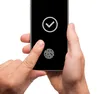 A person's hands are holding a smartphone with a fingerprint scanner and a checkmark icon displayed on the screen. Produktbild-Vorschau