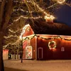 A red barn decorated with Christmas lights and a wreath at night. Produktbild-Vorschau