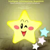 A cartoon star night light with a smiling face, winking, with smaller stars in pink, blue, and white in the background, set against a blurred bedroom background. Produktbild-Vorschau