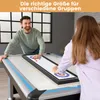 A man and a woman are playing a tabletop shuffleboard and curling game. Produktbild-Vorschau