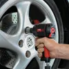 A hand is using a black and red impact wrench to remove a lug nut from a silver Porsche wheel. Anteprima dell’immagine prodotto