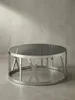 Design-Couchtisch im 3/4-Winkel, der die markante Kreuzstruktur des polierten silbernen Metallgestells unter der dunklen Glasfläche zeigt._#sku_SAFWL6.674# Produktbild-Vorschau