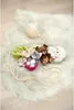 Several small stuffed animals, including cats and a bear, are arranged on a fluffy white rug with a ball of yarn and a string. Produktbild-Vorschau