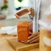 A person is holding the lid of a clear food storage container filled with red lentils. Produktbild-Vorschau