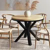 A round dining table with a wood top and black metal base, surrounded by four wooden chairs with woven seats, set in a dining room. Voir les images du produit