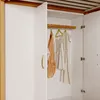 A view inside an open wardrobe with clothes hanging on a rod. Anteprima dell’immagine prodotto
