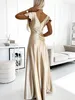 A woman wearing a gold dress in a well-lit room. Produktbild-Vorschau
