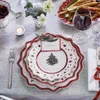 A festive Christmas table setting with plates, cutlery, a wine glass, and a centerpiece. Produktbild-Vorschau