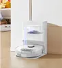 A robot vacuum cleaner is docked at its charging station, which is collecting debris. Produktbild-Vorschau