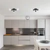 A modern kitchen with light gray cabinets, a stainless steel backsplash, and two black ceiling lights. Náhled obrázku produktu