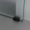 A close-up view of the bottom corner of a glass sliding door with a black fitting attached to the bottom edge. Produktbild-Vorschau