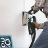 A person is using a Makita wall chaser to cut a groove into a white wall. Podgląd zdjęcia produktu