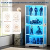 A white glass display cabinet with multiple shelves, illuminated by blue LED lights, showcasing various collectible figures and a motorcycle model. The cabinet is placed in a room with blinds and a marble-patterned pedestal. Náhled obrázku produktu