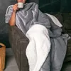 A person sits in a chair wrapped in a gray and white sherpa blanket, holding a mug. Anteprima dell’immagine prodotto