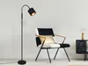 A modern black floor lamp and a black and white armchair with gold accents in a minimalist room. Produktbild-Vorschau