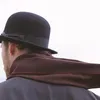 A person wearing a black bowler hat and a brown scarf, seen from behind. Anteprima dell’immagine prodotto