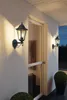 Two outdoor wall lamps illuminate a house entrance at dusk. Anteprima dell’immagine prodotto