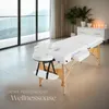 A white massage table set up in a bright, modern room with large windows overlooking a scenic landscape. Náhled obrázku produktu