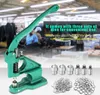 A green manual press machine with various dies and eyelets, set against a blurred background of a factory or workshop with people working. Anteprima dell’immagine prodotto