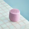 A small, pink, waterproof Bluetooth speaker sits on a tiled surface next to a pool of water. Náhľad obrázku produktu