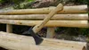 An axe is stuck into a wooden bench in an outdoor setting. Anteprima dell’immagine prodotto