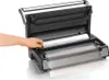 A hand is shown placing a roll of vacuum seal bag material into a vacuum sealing machine. Podgląd zdjęcia produktu