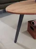 A close-up of a coffee table leg and part of the tabletop, resting on a rug. Voir les images du produit