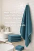A bathroom scene with a teal towel hanging on a hook and folded towels on a shelf. Produktbild-Vorschau