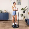 A woman is using a stepper machine in a living room. Voir les images du produit