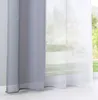 A close-up view of two curtains hanging side-by-side in front of a window, with a garden visible outside. Produktbild-Vorschau