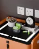 A desk setup with a plant, battery charger, clock, and books. Produktbild-Vorschau