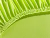 A close-up view of a lime green fitted sheet with elasticized edges. Produktbild-Vorschau