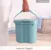 A person is holding a blue diaper pail with a lid and handle. Produktbild-Vorschau