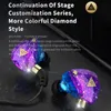 A pair of colorful, glittery in-ear headphones with a black cable against a dark background. Produktbild-Vorschau