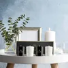 A set of four scented candles arranged on a white table, with a vase of eucalyptus and a picture frame in the background. Produktbild-Vorschau