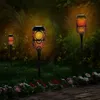 Three solar-powered garden lights with a flame effect are illuminating a garden path at dusk. Produktbild-Vorschau