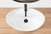 A white oval sink with a black faucet and drain, placed on a wooden surface. Náhled obrázku produktu