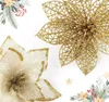 Two artificial poinsettia flowers, one gold and one white with gold trim, are displayed against a white background with decorative greenery and berries in the corners. Podgląd zdjęcia produktu