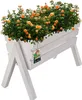 A white wooden planter box filled with orange roses, elevated on legs. Produktbild-Vorschau